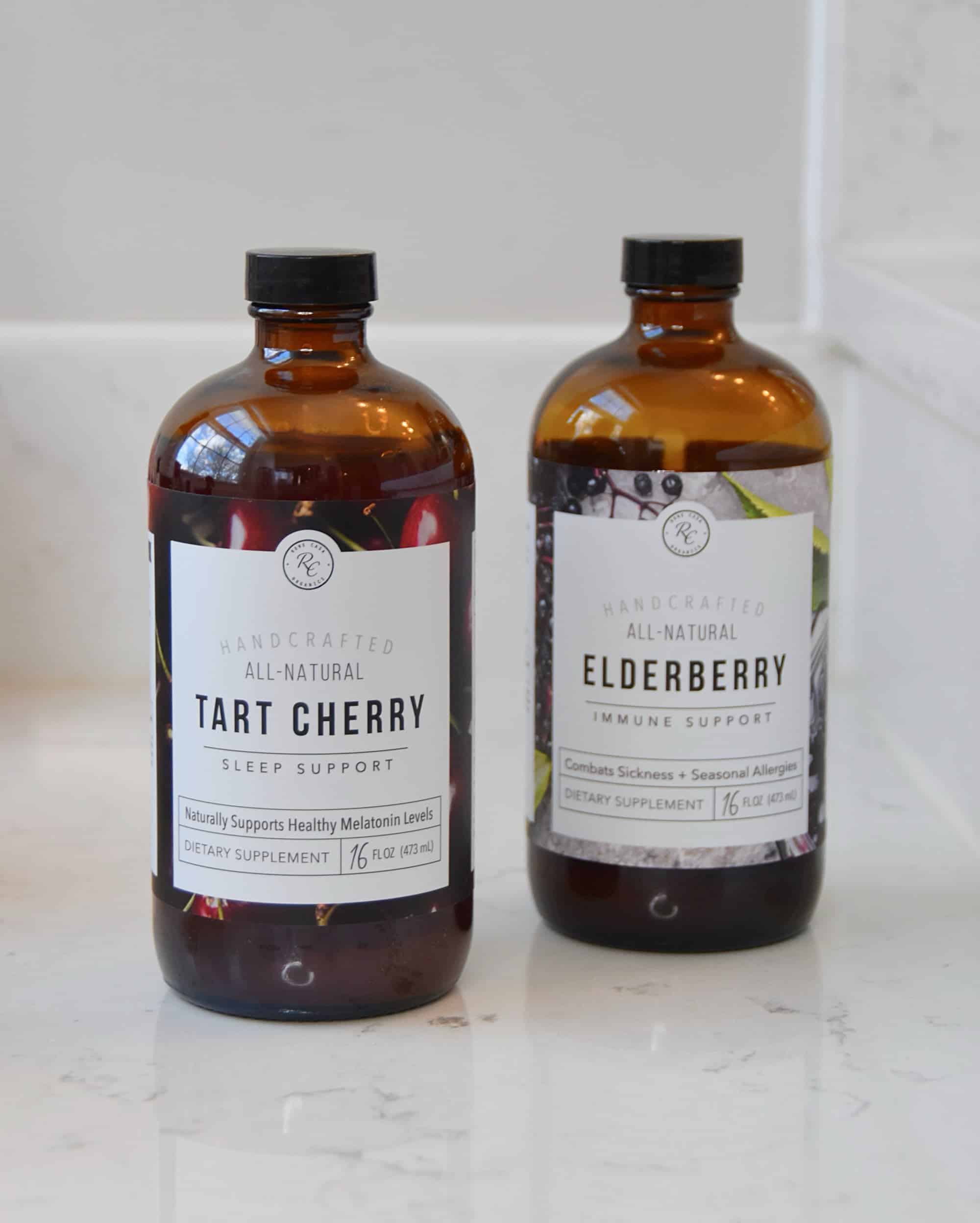 A bottle of the Rowe Casa Organics Tart Cherry Sleep Support and Elderberry Immune Support side by side on the counter.