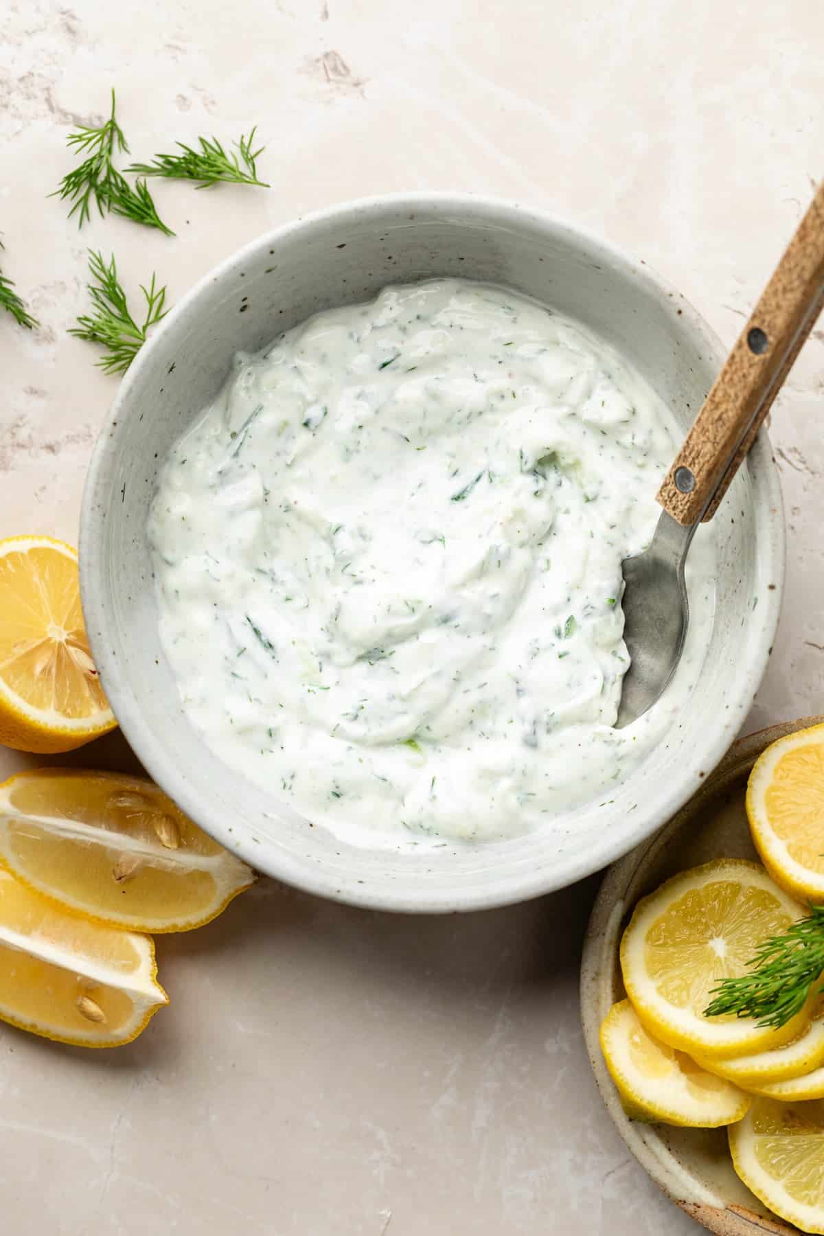 A bowl of homemade Tzatziki sauce made with greek yogurt, shredded cucumber, garlic, olive oil, lemon juice, and dill.